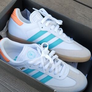Adidas Samba White Sneakers with Teal Stripes and Orange Heel Accents.